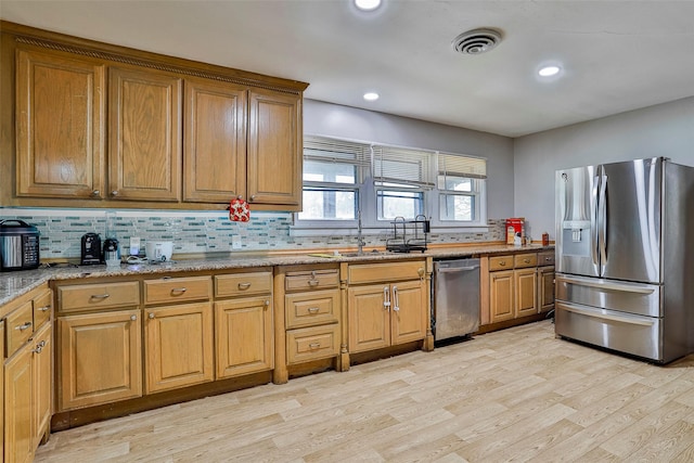 kitchen with tasteful backsplash, stainless steel appliances, light hardwood / wood-style floors, and sink