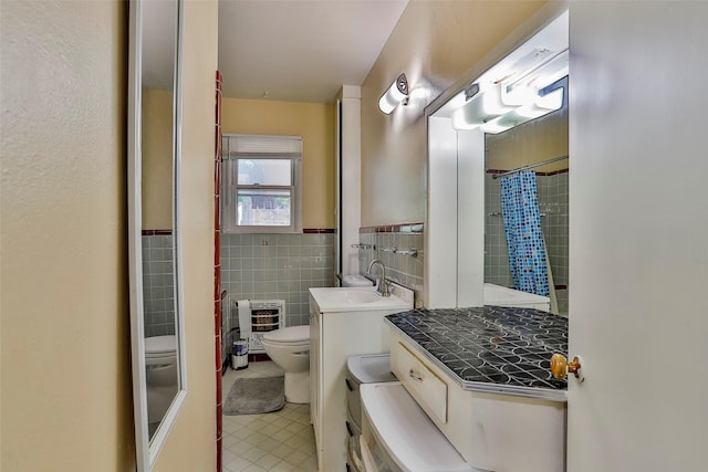 bathroom featuring tile walls, vanity, heating unit, tile patterned floors, and toilet