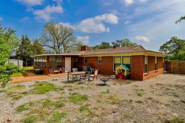 rear view of house featuring a fire pit, a patio area, a sunroom, and central air condition unit