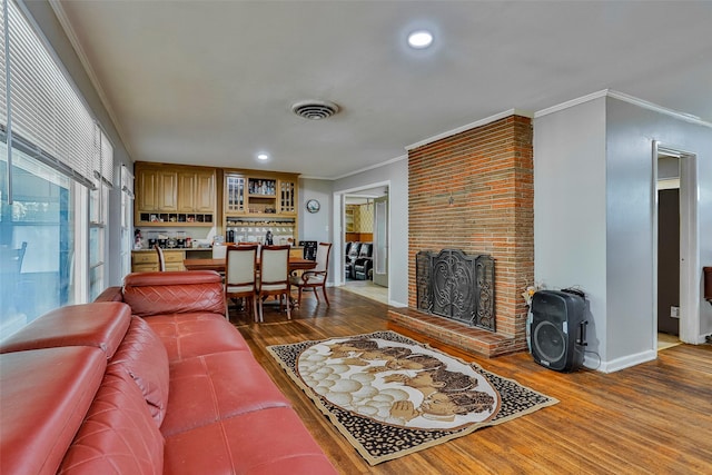 living room featuring hardwood / wood-style flooring, crown molding, and a fireplace