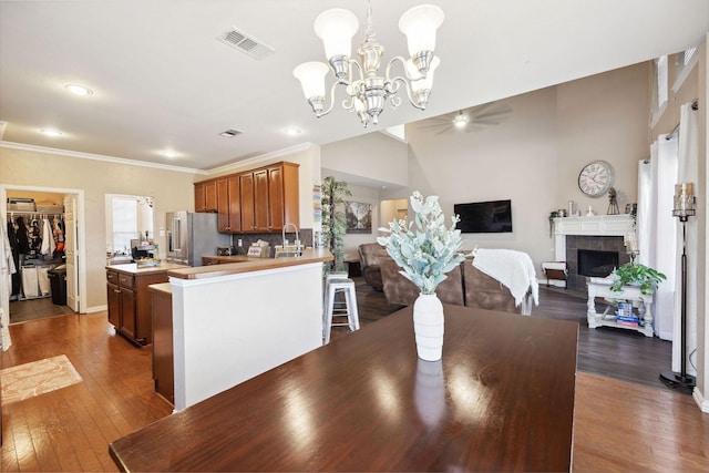 dining space with a tiled fireplace, crown molding, and dark wood-type flooring