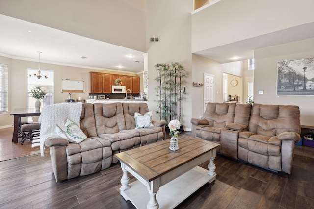 living room with sink, crown molding, a chandelier, dark hardwood / wood-style floors, and a high ceiling