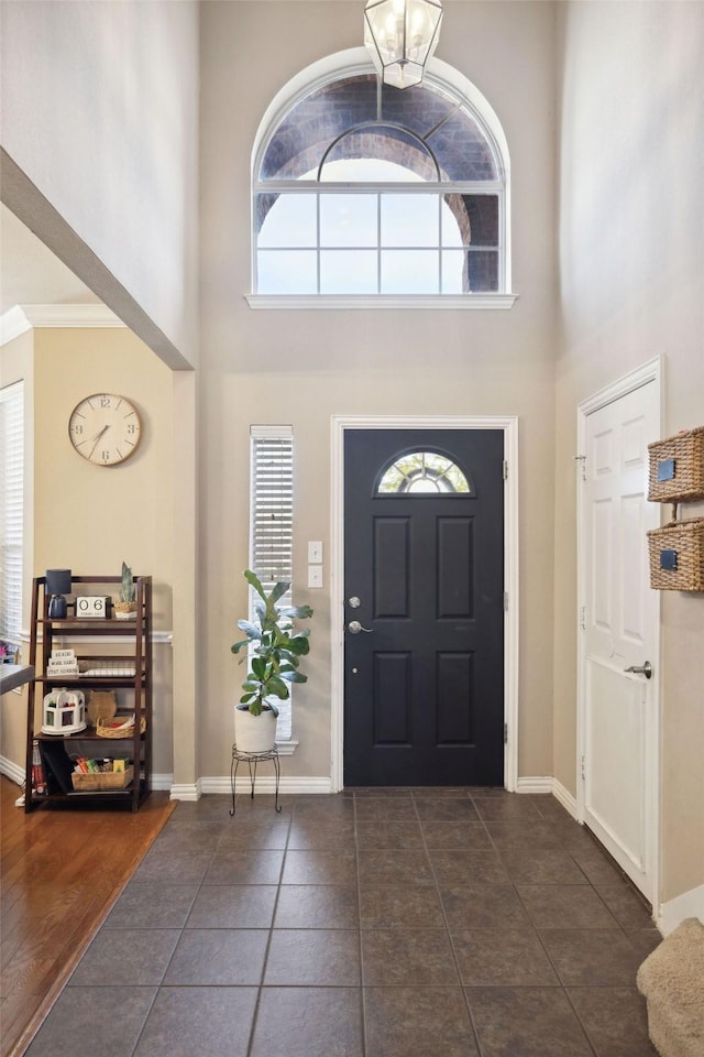 foyer entrance featuring a towering ceiling and dark tile patterned flooring