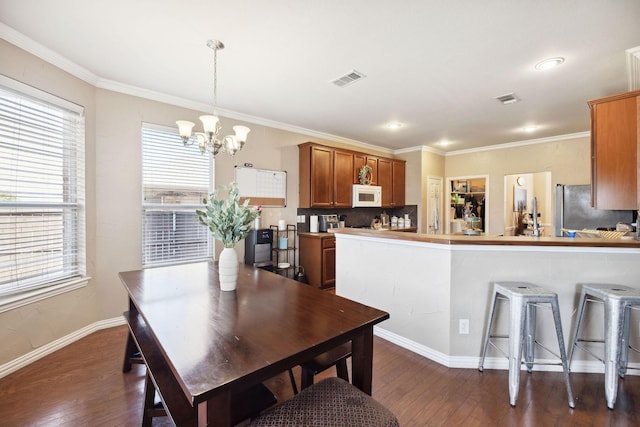 dining room featuring dark hardwood / wood-style flooring, crown molding, and an inviting chandelier