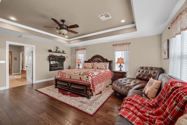 bedroom featuring a raised ceiling, ceiling fan, crown molding, and dark hardwood / wood-style flooring
