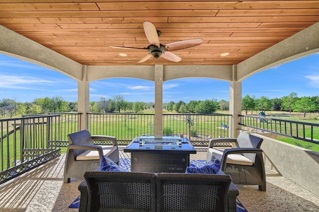view of patio / terrace with ceiling fan and an outdoor living space with a fire pit
