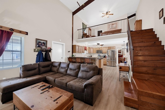 living room featuring ceiling fan, a towering ceiling, and light wood-type flooring