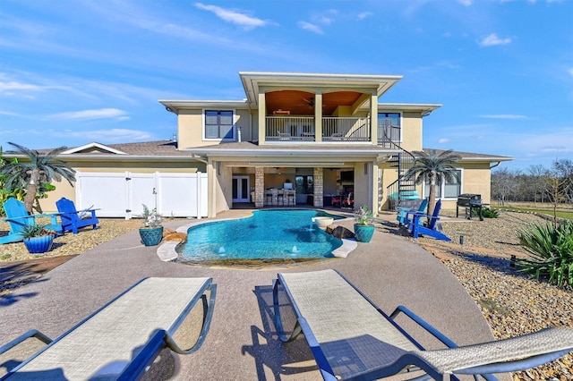 back of house featuring pool water feature, a balcony, ceiling fan, and a patio area