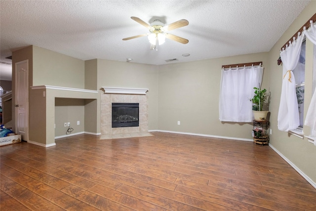 unfurnished living room with dark hardwood / wood-style flooring, a textured ceiling, a fireplace, and ceiling fan