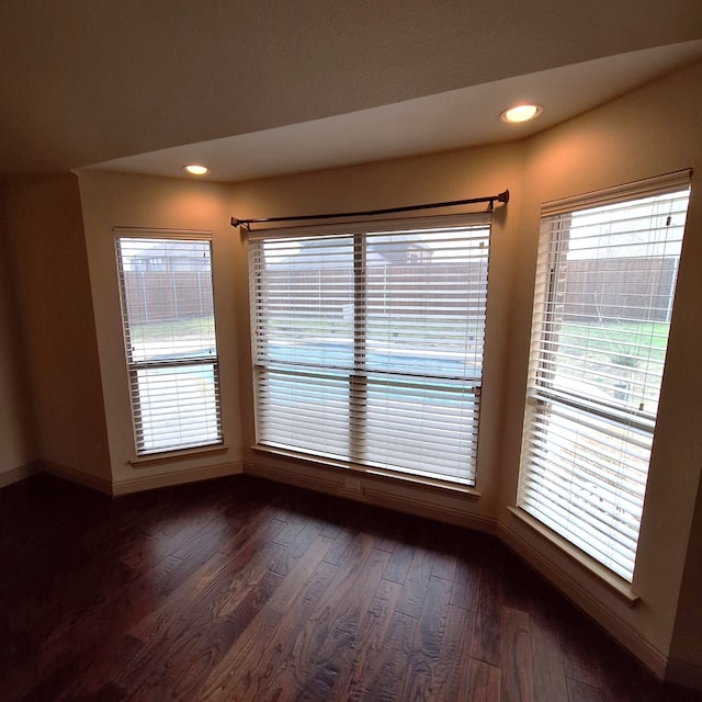 spare room with dark wood-style floors, recessed lighting, a healthy amount of sunlight, and baseboards