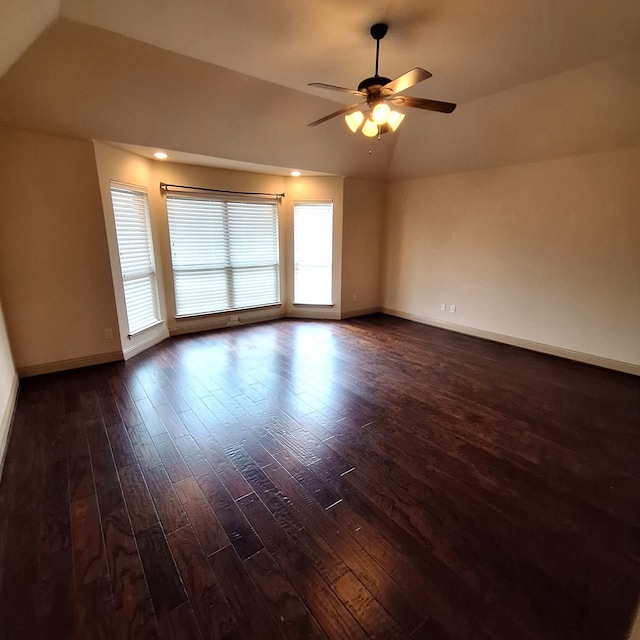 spare room featuring dark wood-style floors, ceiling fan, baseboards, and vaulted ceiling