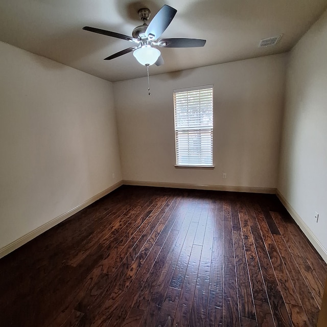 empty room featuring dark wood-type flooring, visible vents, baseboards, and a ceiling fan