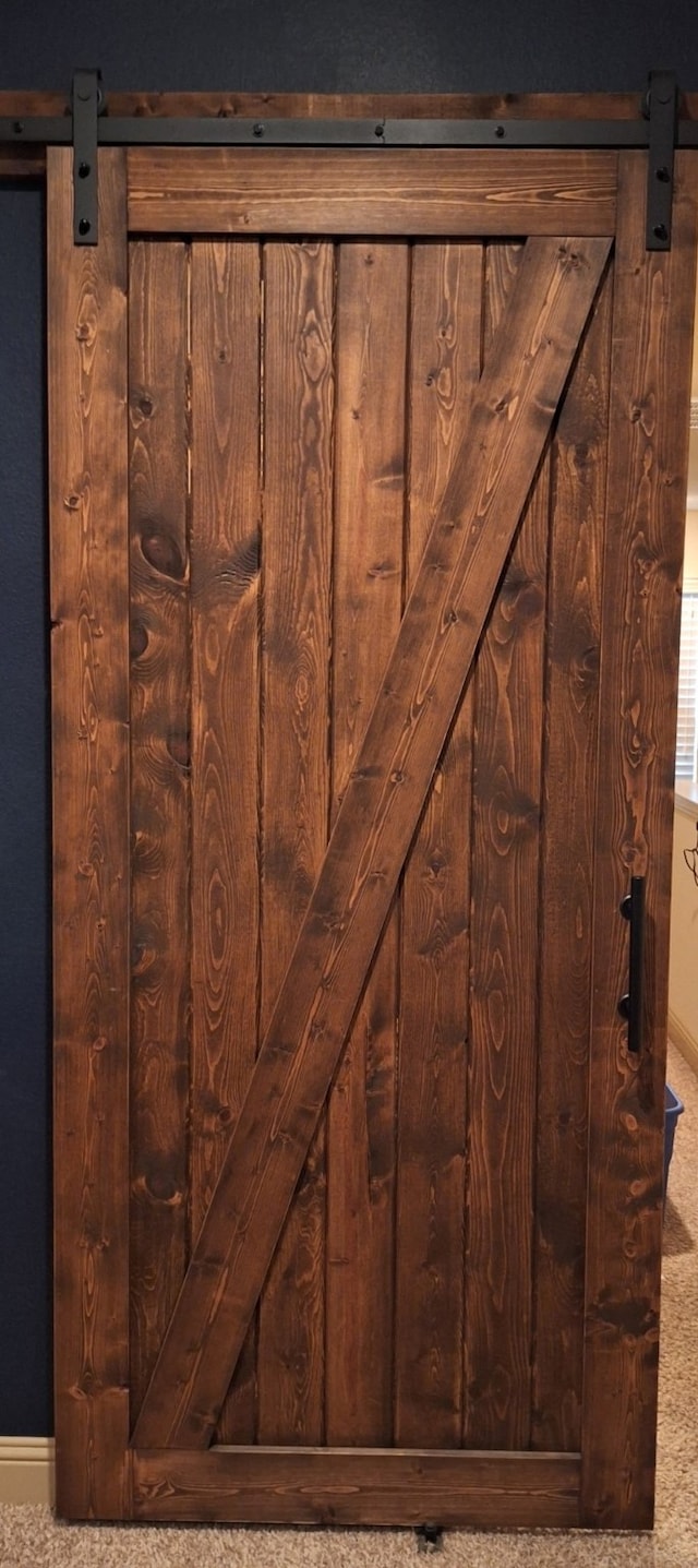 room details with a barn door, carpet, and baseboards