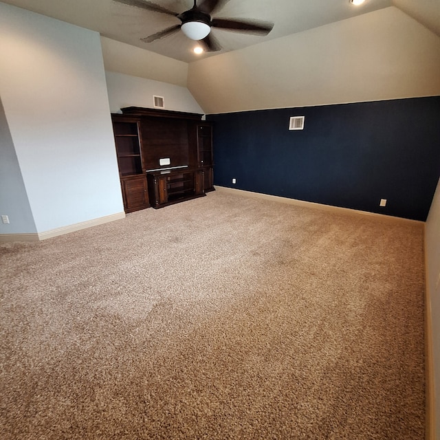 interior space featuring carpet, vaulted ceiling, visible vents, and ceiling fan