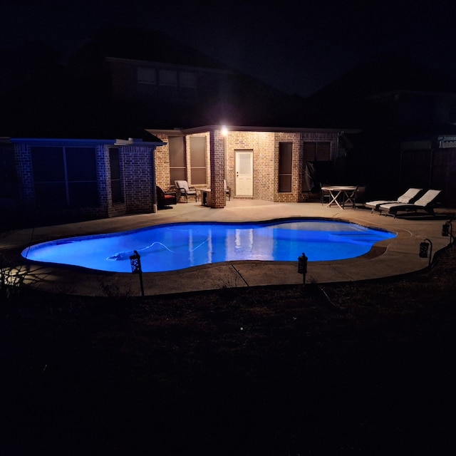 pool at twilight featuring a patio area and an outdoor pool