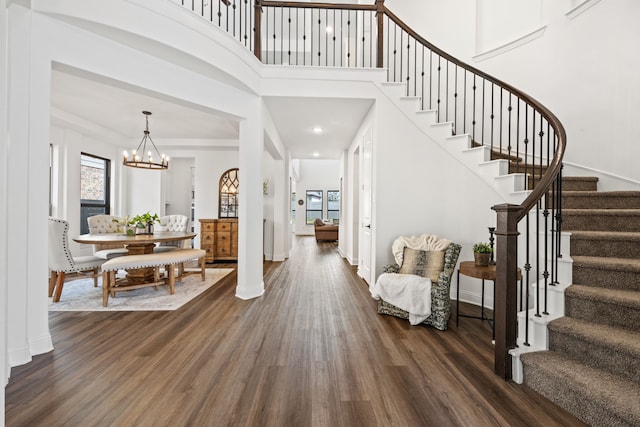 foyer with a chandelier, dark wood-type flooring, a high ceiling, baseboards, and stairs