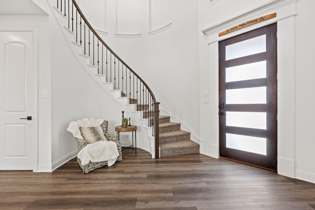 entryway with dark wood-type flooring and a towering ceiling