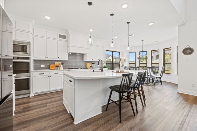 kitchen featuring white cabinets, appliances with stainless steel finishes, backsplash, light countertops, and a sink