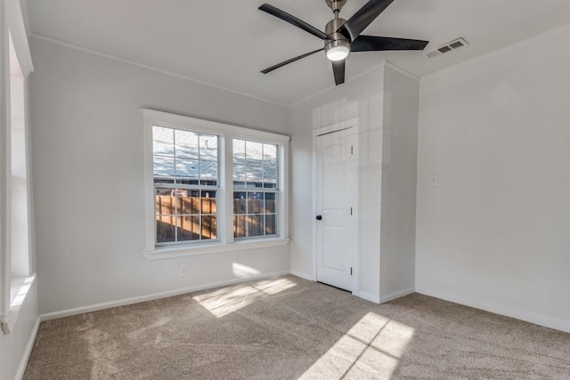 empty room with light carpet, ornamental molding, and ceiling fan