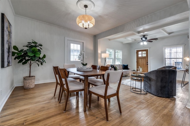 dining room featuring beam ceiling, ornamental molding, a wealth of natural light, and light hardwood / wood-style floors