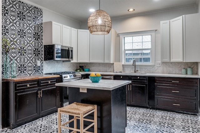 kitchen with sink, crown molding, a breakfast bar, white cabinetry, and a center island