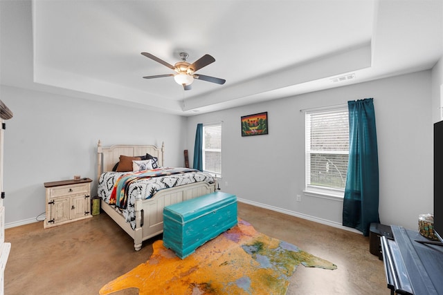 bedroom featuring multiple windows, a raised ceiling, and ceiling fan