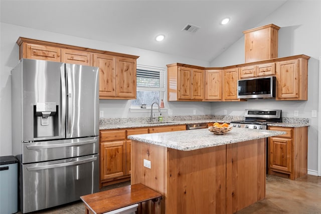 kitchen with vaulted ceiling, a kitchen island, appliances with stainless steel finishes, sink, and light stone counters