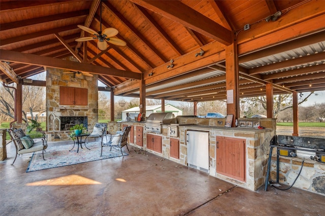 view of patio / terrace with a gazebo, an outdoor kitchen, a grill, and an outdoor stone fireplace