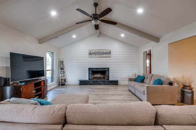 living room featuring light hardwood / wood-style flooring, vaulted ceiling with beams, a high end fireplace, and ceiling fan