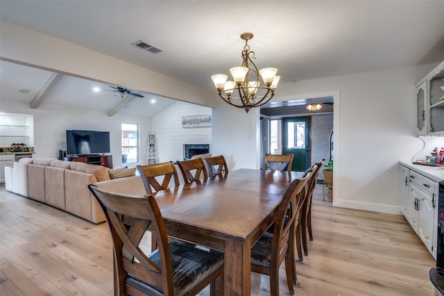 dining room featuring lofted ceiling with beams, ceiling fan with notable chandelier, and light wood-type flooring