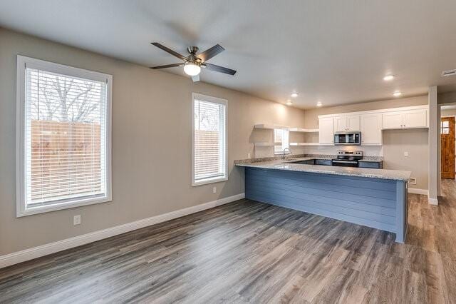 kitchen with white cabinetry, sink, hardwood / wood-style flooring, kitchen peninsula, and stainless steel appliances