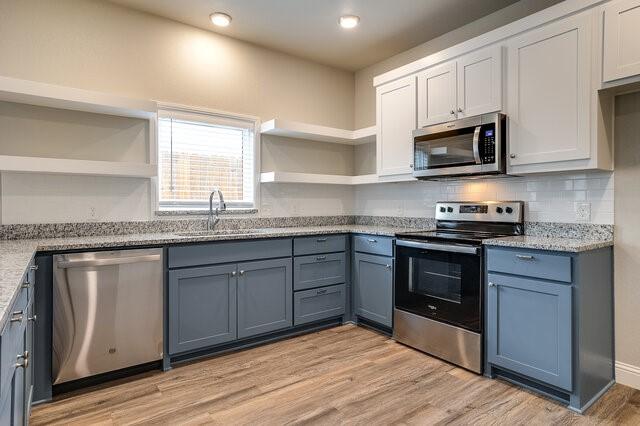 kitchen featuring appliances with stainless steel finishes, sink, white cabinets, and light wood-type flooring