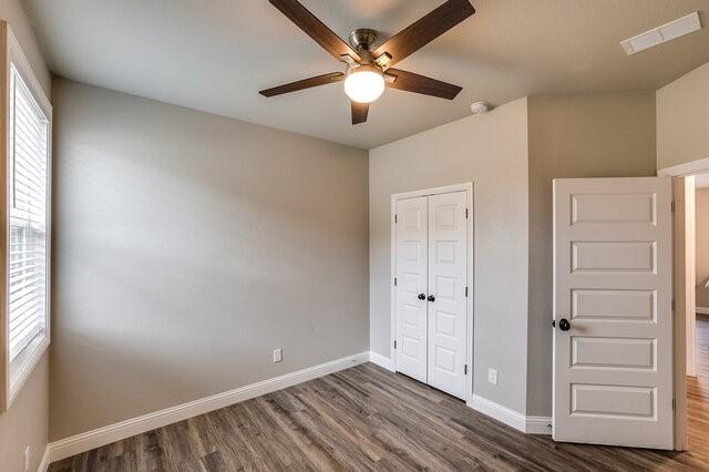 unfurnished bedroom with dark wood-type flooring, ceiling fan, and a closet