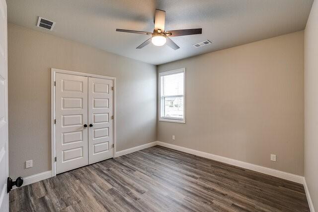 empty room with dark wood-type flooring and ceiling fan