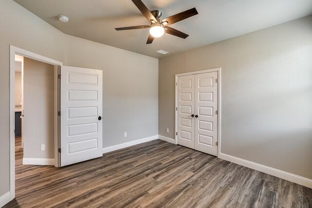 unfurnished bedroom with dark wood-type flooring, ceiling fan, and a closet