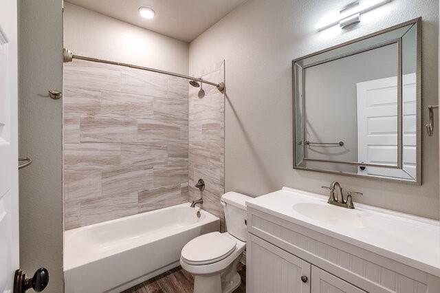 full bathroom with hardwood / wood-style flooring, vanity, toilet, and tiled shower / bath combo