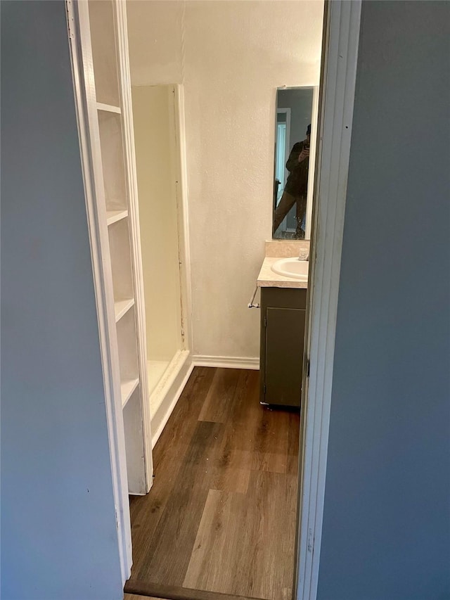 bathroom with wood finished floors, vanity, and baseboards