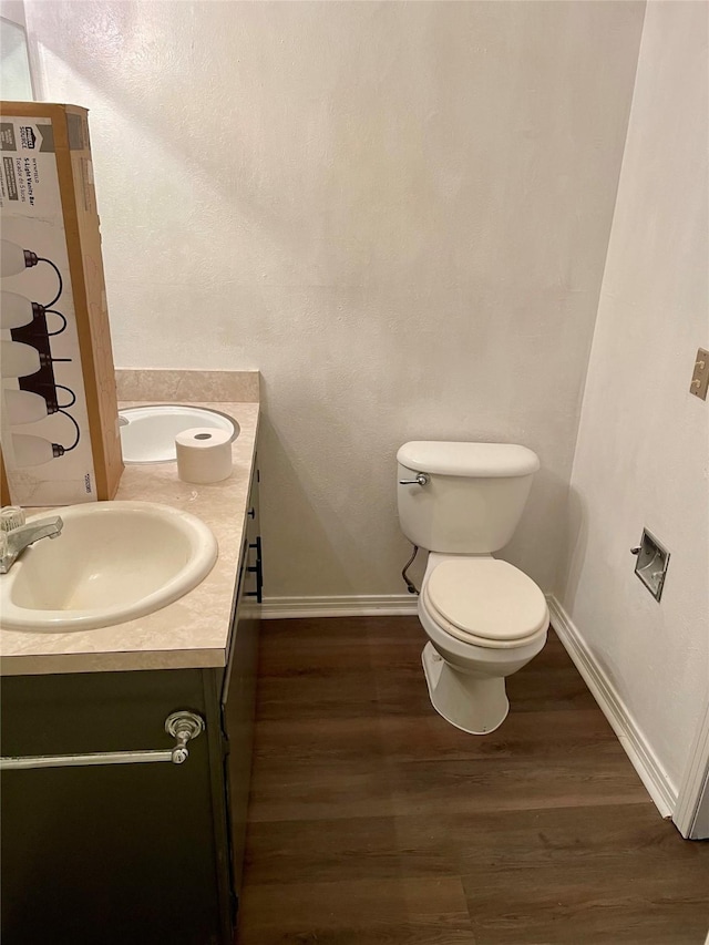 bathroom featuring toilet, wood finished floors, vanity, and baseboards