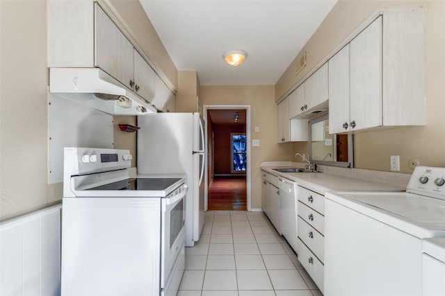 kitchen with light tile patterned flooring, white appliances, sink, and washing machine and dryer