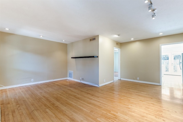 empty room featuring light hardwood / wood-style flooring and track lighting