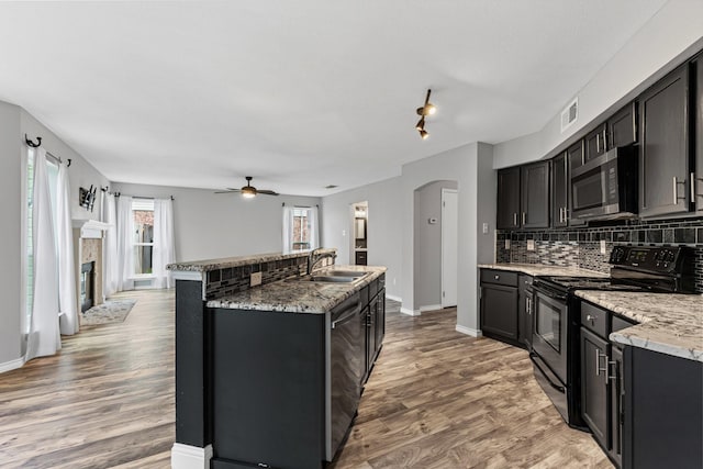 kitchen with appliances with stainless steel finishes, sink, backsplash, and light stone counters