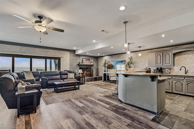 living room with a lit fireplace, a ceiling fan, visible vents, and recessed lighting