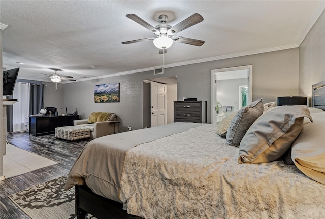 bedroom with a ceiling fan, wood finished floors, ornamental molding, and visible vents