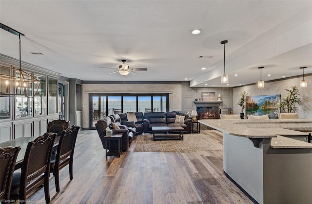 living room with ceiling fan, ornamental molding, and light wood-type flooring