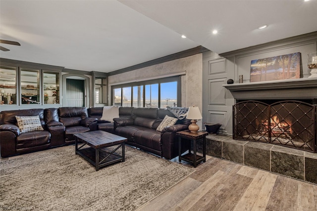 living area with a tiled fireplace, ceiling fan, crown molding, recessed lighting, and wood finished floors