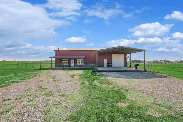 view of front of house featuring an outbuilding, a garage, a front yard, and a rural view