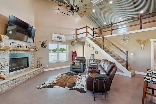 living room with a stone fireplace, ceiling fan, and a high ceiling