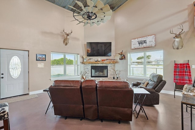 living room with concrete flooring, plenty of natural light, a towering ceiling, and a fireplace