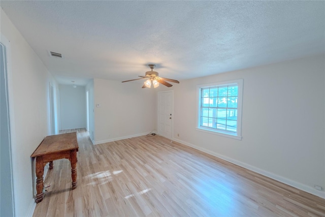 unfurnished room with ceiling fan, a textured ceiling, and light hardwood / wood-style flooring