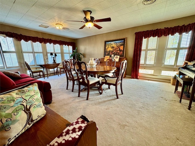 carpeted dining area with ceiling fan